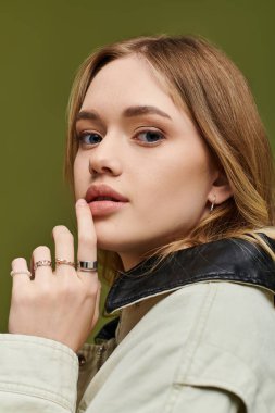 Şık bir genç kadın şık kıyafetlerini ve zarif aksesuarlarını sergileyerek düşünceli bir şekilde poz verir..