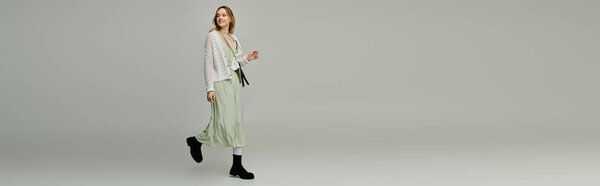 Уверенная в себе молодая женщина демонстрирует свой стильный весенний наряд в минималистском пространстве, излучая очарование.