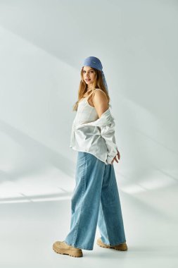Modayı takip eden genç bir kadın canlı bir bahar kıyafetini gri bir zemine karşı modelliyor..