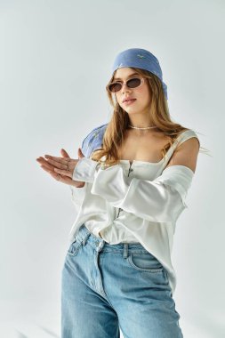 Modayı takip eden genç bir kadın, gri bir arka planda, gençlik titreşimleri yayan bir bahar elbisesi modelliyor..