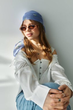 Şık bir genç kadın, minimalist bir stüdyoda canlı bir bahar elbisesi sergiliyor..