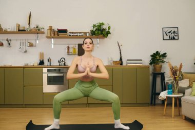 Genç, sportif bir kadın evde yoga yapıyor. Odaklanma ve denge gösteriyor..