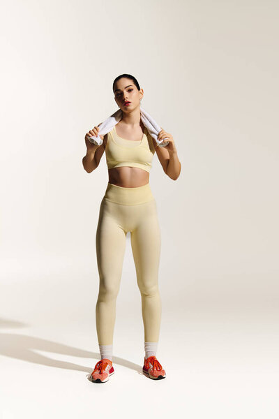 Young beautiful and athletic woman confidently poses in fitted workout attire, emanating strength.