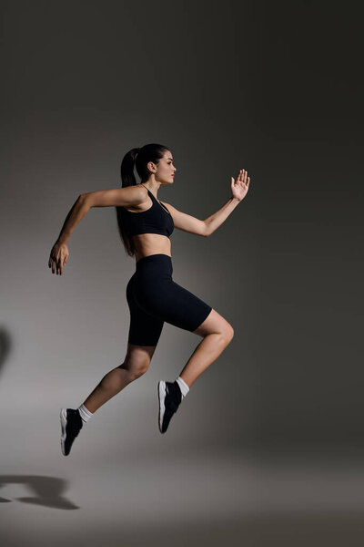 Целенаправленная молодая женщина целенаправленно бежит, демонстрируя свой атлетизм в яркой сцене.