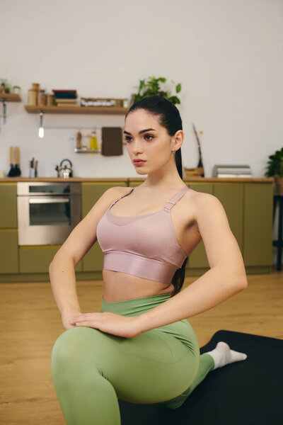 Young and beautiful woman stretches gracefully in a serene indoor environment, focusing on fitness.