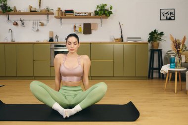 Genç ve güzel bir kadın, esnekliğini ve rahatlığını arttırmak için evde yoga pratiği yapıyor..