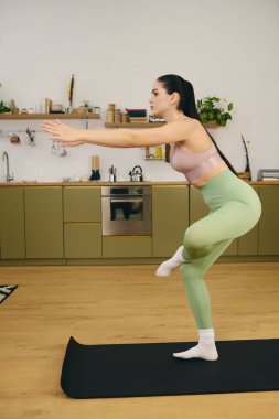 Genç atletik kadın içeride egzersiz yaparken etkileyici bir denge ve odaklanma gösteriyor.