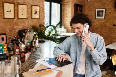 Tarz sahibi genç bir adam bir kafede dinleniyor, tabletini keşfederken bir telefon görüşmesi yapıyor..