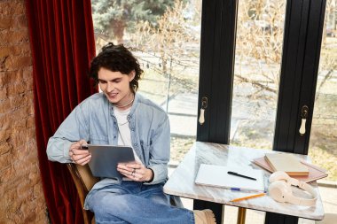 Genç yakışıklı bir adam bir kafede rahatça oturup sakin bir öğleden sonranın tadını çıkarırken tableti karıştırıyor..