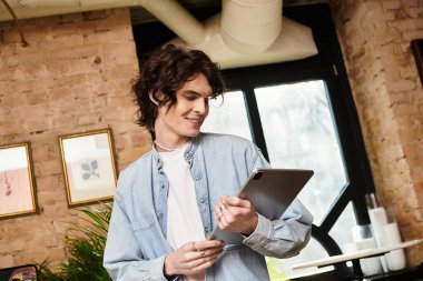 Genç bir adam elinde bir tablet tutarken gülümsüyor, bir kafede dinlenme anına dalmış..