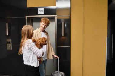 Genç bir çift otel lobisinde sevimli bir anı paylaşıyor. Yanında da sevimli köpekleri var..