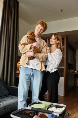 Sevgi dolu bir çift, rahat bir otel odasında keyifle gülümser, köpekleriyle güzel vakit geçirirler..