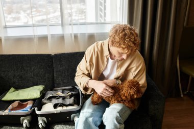 Genç adam, sevimli köpeğiyle bağ kurarken kaldığı otelde neşeyi paylaşıyor.