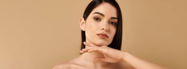 Genç bir kadın, sakin bir stüdyoda zarifçe poz verirken ışıl ışıl tenini sergiliyor.