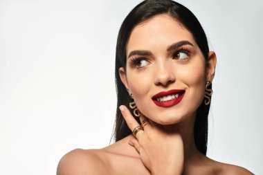 Kahverengi saçlı güzel bir genç kadın zarif poz verirken parlak kırmızı dudaklarını sergiliyor..