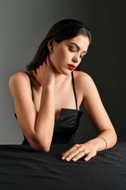 Kahverengi saçlı ve çarpıcı kırmızı dudaklı genç bir kadın tarafsız bir arkaplanda güzellik yayıyor..