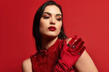 Çekici kahverengi saçlı ve kalın kırmızı dudaklı genç bir kadın zarif bir moda sergiliyor..