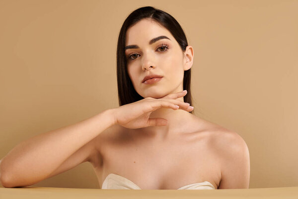 A young woman showcases her radiant skin in a minimalist studio, highlighting skincare.