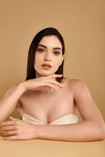 A young woman presents her flawless, glowy skin while relaxing in a calming studio atmosphere.