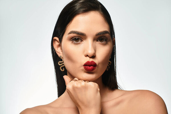 Breathtaking young woman showcases her beauty with captivating red lips and flawless makeup.
