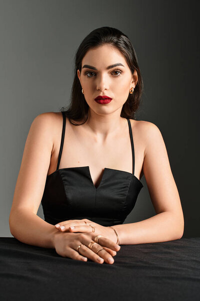 Красивая молодая женщина с каштановыми волосами и красными губами демонстрирует свое искусство макияжа.