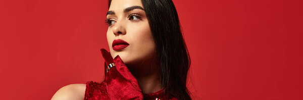 Красивая молодая женщина с красными губами элегантно позирует на ярком красном фоне, баннер