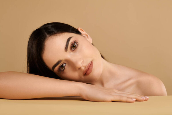 A young woman highlights her glowing complexion while relaxing in a tranquil studio environment.