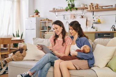 İki anne, bebekleriyle gülümsemelerini paylaşarak rahat evlerinde anneler gününün tadını çıkarırlar..