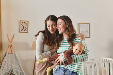 İki mutlu anne, anneler gününü bebekleriyle birlikte sıcacık bir evde kutluyor.