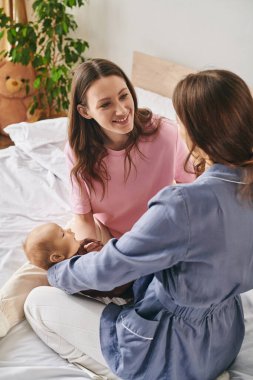 İki neşeli anne, evde huzurlu bir günün tadını çıkarırken, bebekleriyle hassas bir anı paylaşıyor..