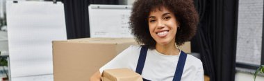 Neşeli kadın şık ve modern bir ortamda taşınmak için kutuları ustalıkla paketliyor..