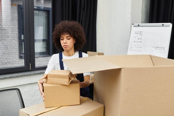 A woman carefully packs boxes, preparing for a modern moving process with focus.