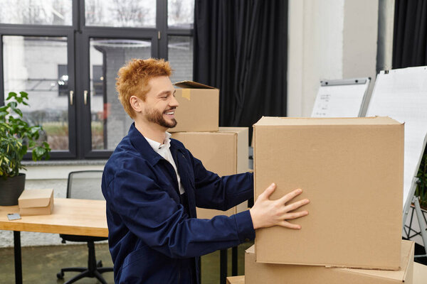 Young man joyfully packing boxes in a modern office, showing enthusiasm for the move.