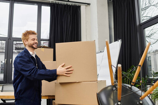Happy man lifts boxes in a modern office on moving day.