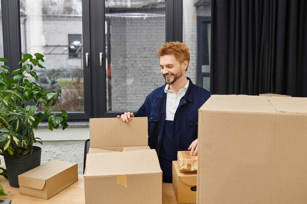 A man happily sorts through boxes in a modern office, getting ready to unpack.