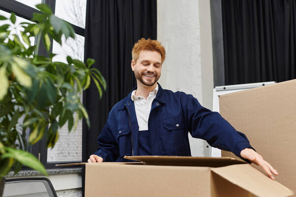 A young man joyfully unpacks boxes in a contemporary office, embracing the moving adventure ahead.