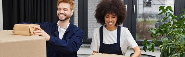 Two individuals joyfully pack boxes in their contemporary apartment, preparing for a big move.