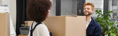 İki mutlu insan, modern bir çalışma alanında kutuları paketleyip taşınmaya hazırlanıyorlar..