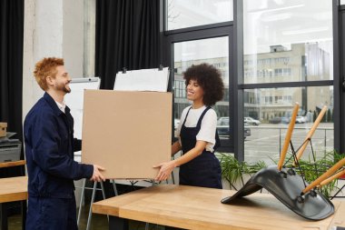 Çağdaş bir ofis ortamında iki birey kutuları paketlemek ve açmak için birlikte çalışıyorlar..
