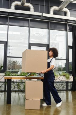Bir kadın, hareket ruhunu somutlaştıran çağdaş bir ortamda büyük bir karton kutuyu kaldırır..