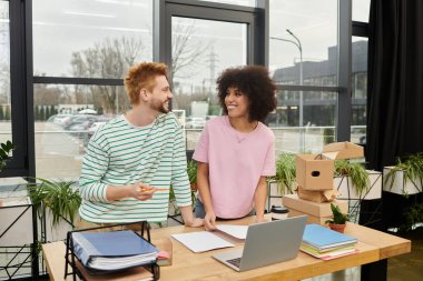 Çağdaş bir ofis ortamında iki iş arkadaşı aktif olarak paketleme ve boşaltma görevleri yapmaktadır.