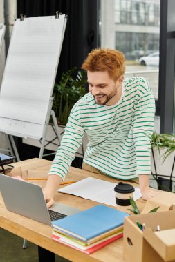 Genç bir adam ofis malzemeleri ve evraklarını hazırlarken notlar alır..