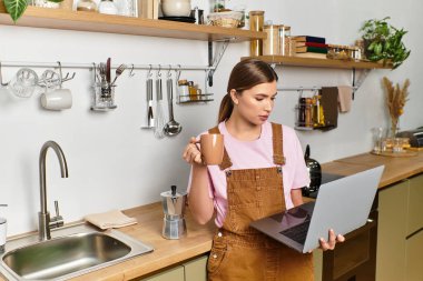 Genç bir kadın çalışırken kahvesini yudumlarken doğal ışıkla dolu parlak ve davetkar bir mutfak..