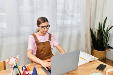 Modern giyimli kadın dizüstü bilgisayarına odaklanmış, bitkiler, bayraklar ve çalışma materyalleriyle çevrili..