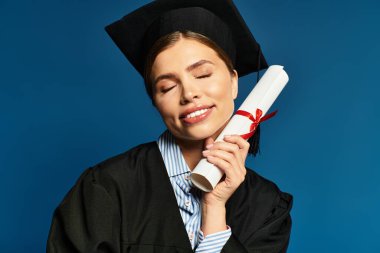 Genç ve güzel bir kadın gururla gülümserken diplomasını parlak mavi bir arka planda tutuyor.