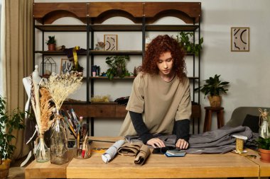 Parlak bir odada kumaş ve malzemeleri düzenlerken DIY zanaatı yapan genç ve güzel bir kadın..