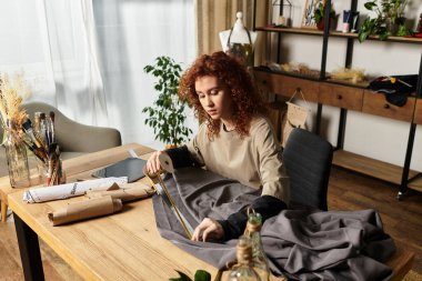 Yetenekli genç bir kadın yaratıcı stüdyosundaki DIY projesi için kumaş ölçümü yapıyor..