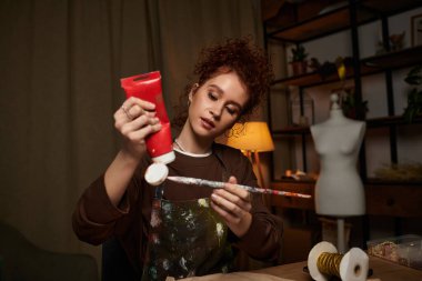 Yetenekli genç bir kadın DIY projesine dalmış, titizlikle ve dikkatle resim yapıyor..