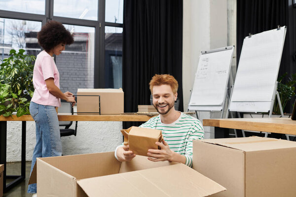 Two people happily pack and unpack boxes in a modern office.