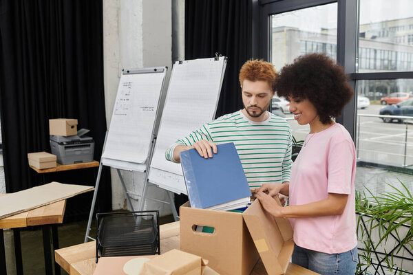 Two people happily organize their things, getting ready to move in a modern workspace.